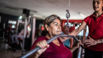 Movement exercise: isolation: trainer helping with weight machine 1435831738 