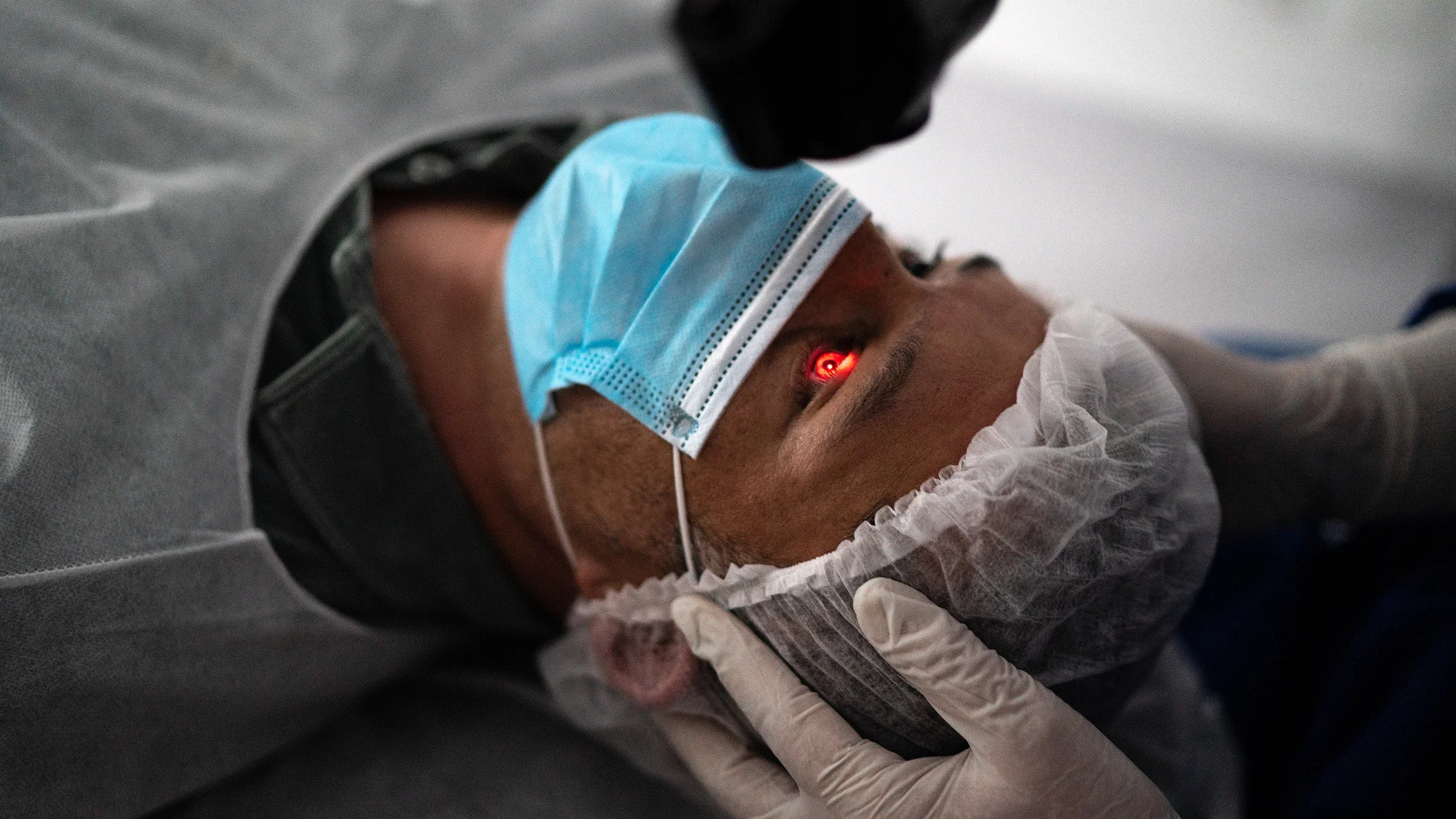 Close-up of a patient undergoing eye surgery. You can see a red circular laser on their pupil.
FG Trade/iStock via Getty Images