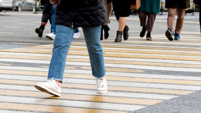 A cropped shot of people's feet crossing an intersection.