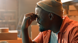 A man pinches the bridge of his nose as he grimaces in pain from a migraine.
Bevan Goldswain/E+ via Getty Images