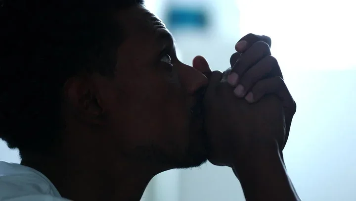 A person holds their hands to their face