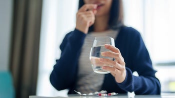 Allergies: woman holding water and taking medication 2158925213