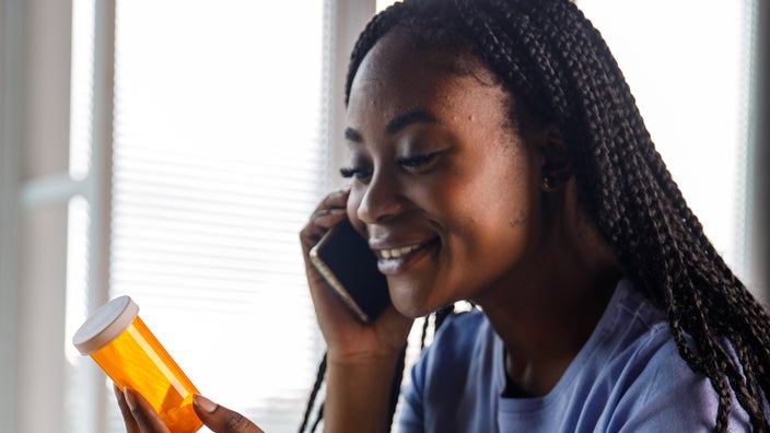 Young adult on a phone call, holding a pill bottle 