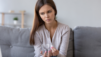 Birth control: Vitamin deficiencies: pensive taking pill on couch-1150540131
