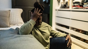 Mental Health: Depression: upset woman sitting on bedroom floor 1435658769