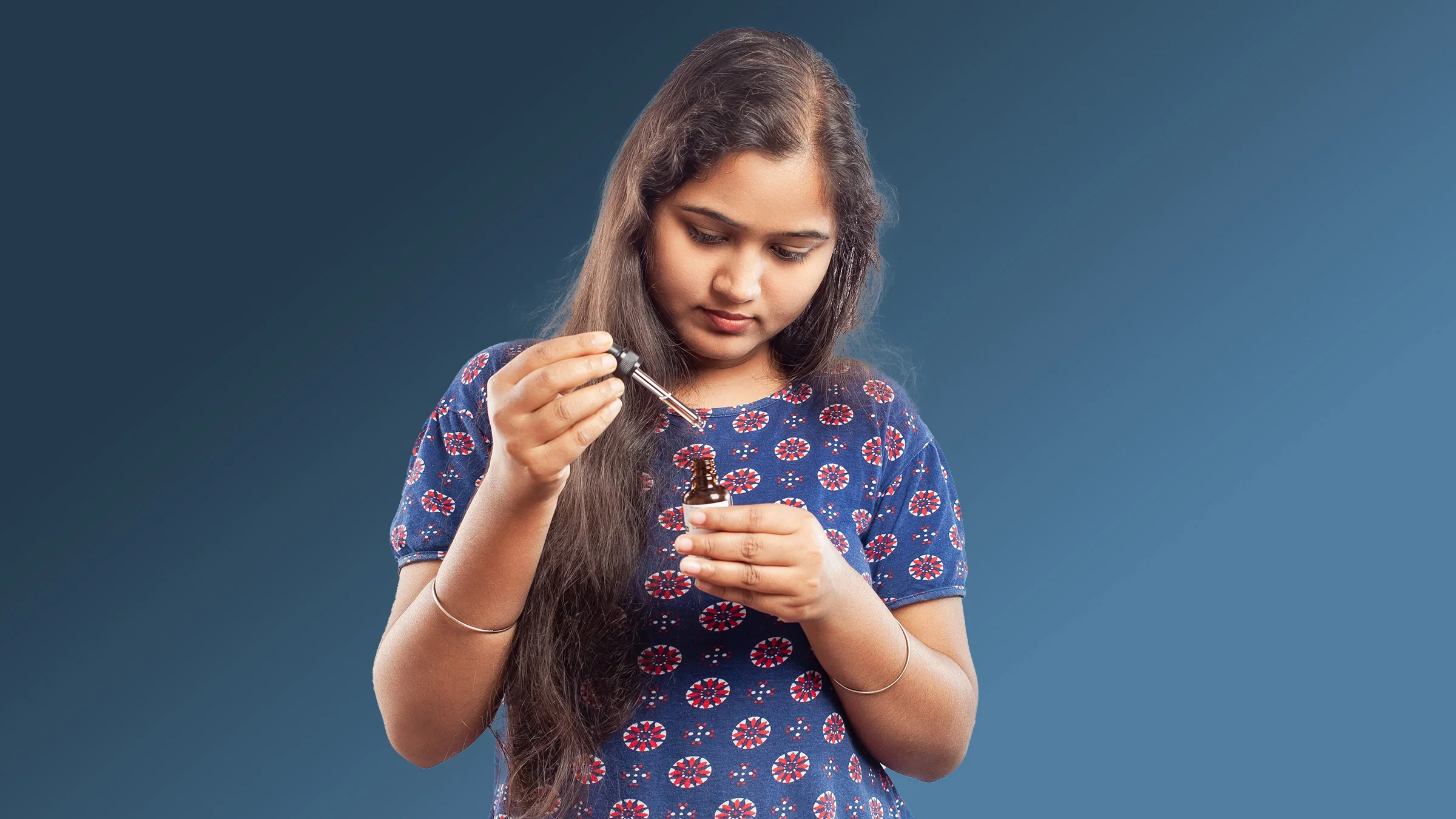 A woman opens a bottle of essential oil. 