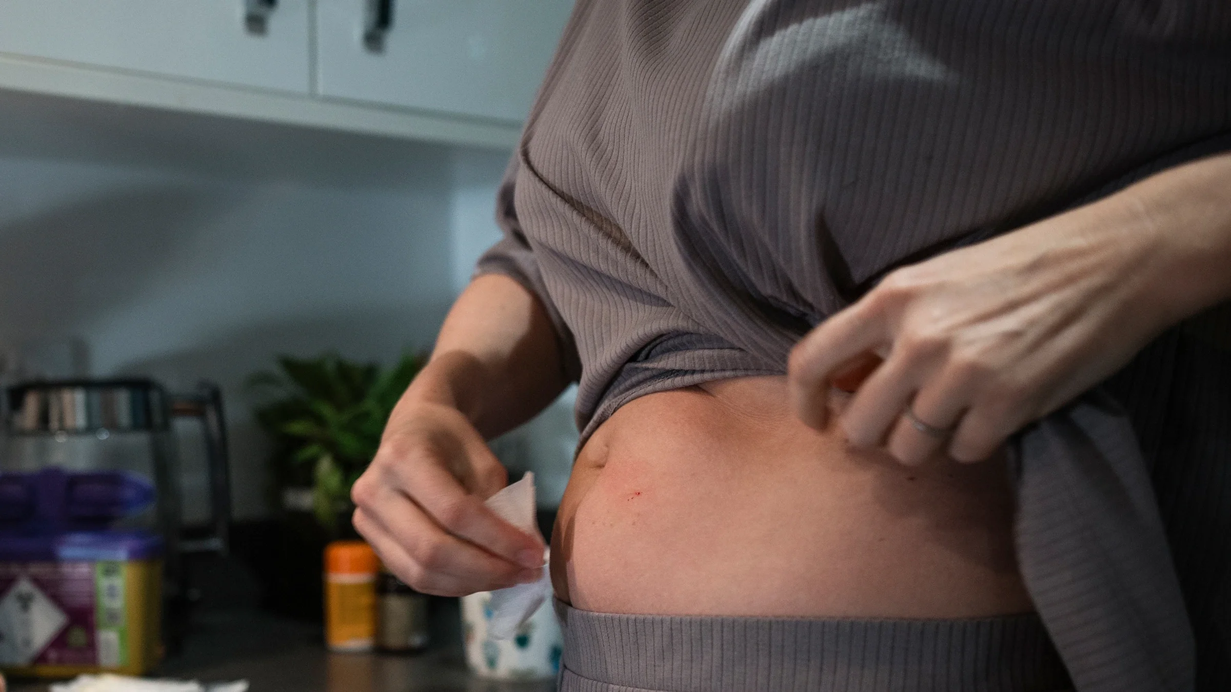 A woman cleans an injection site with an alcohol pad.