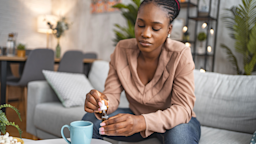 Woman dosing her CBD while sitting in her living room
Viktor Cvetkovic/E+ via Getty Images 