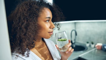 Diet and nutrition: woman drinking cucumber water 1256771760