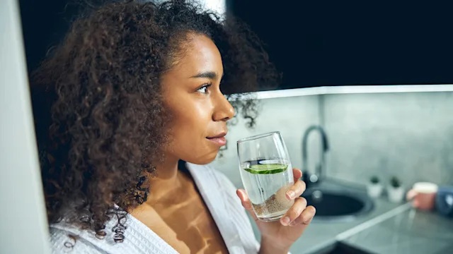 Diet and nutrition: woman drinking cucumber water 1256771760