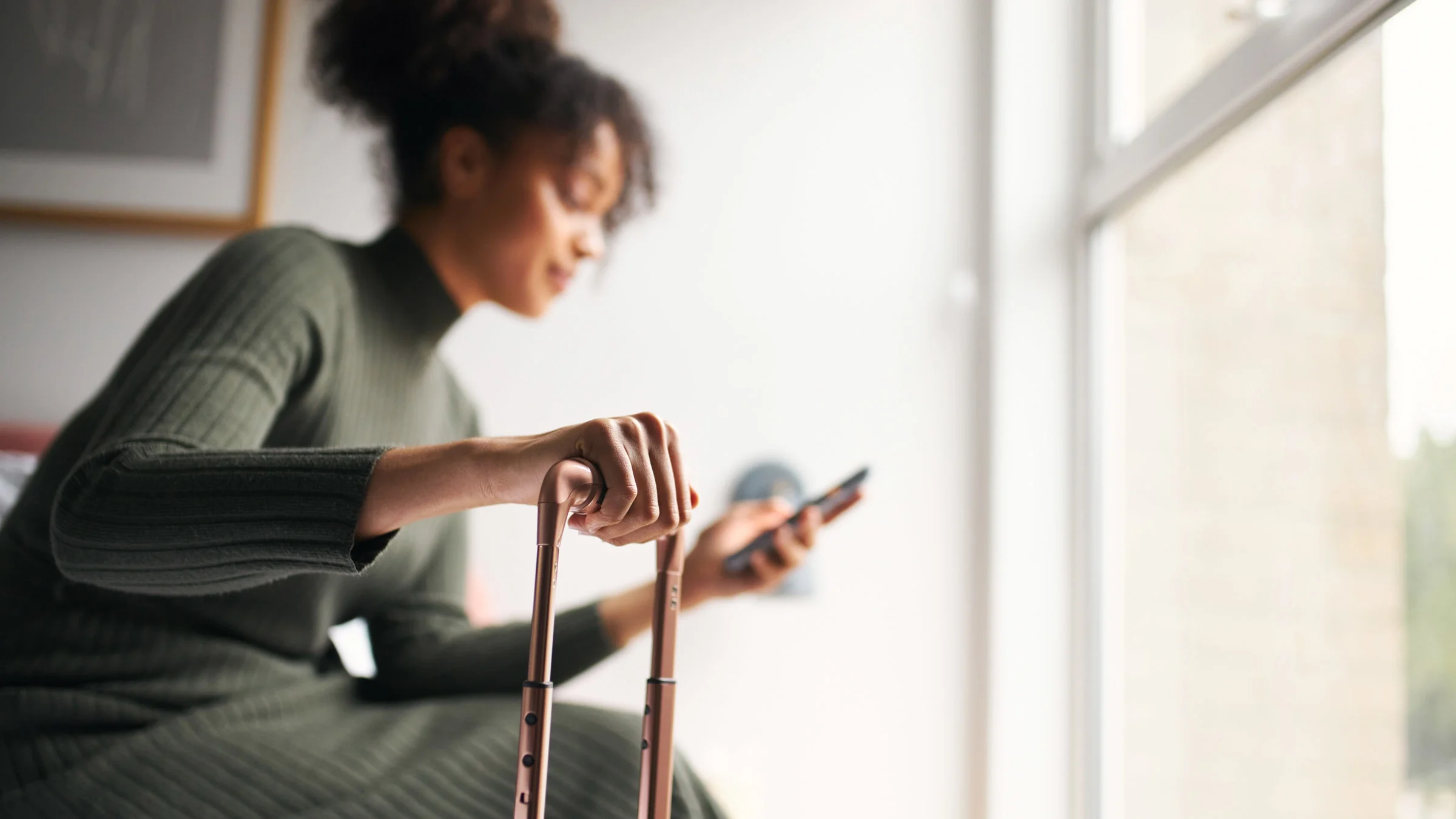 A person sitting and holding a suitcase, getting ready to go.