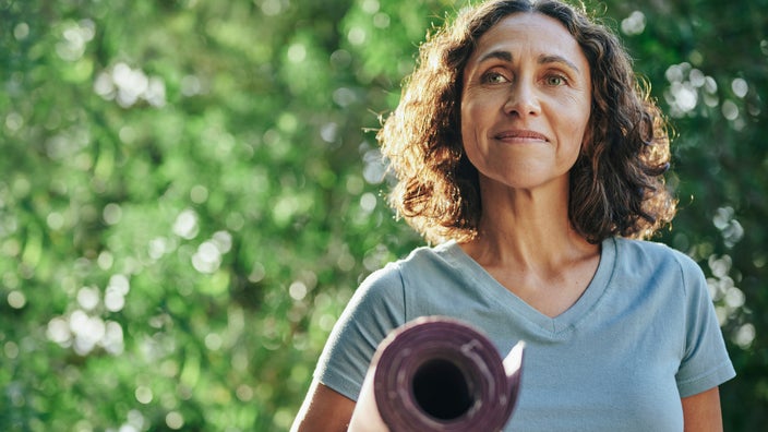 A menopausal woman carrying a yoga mat.