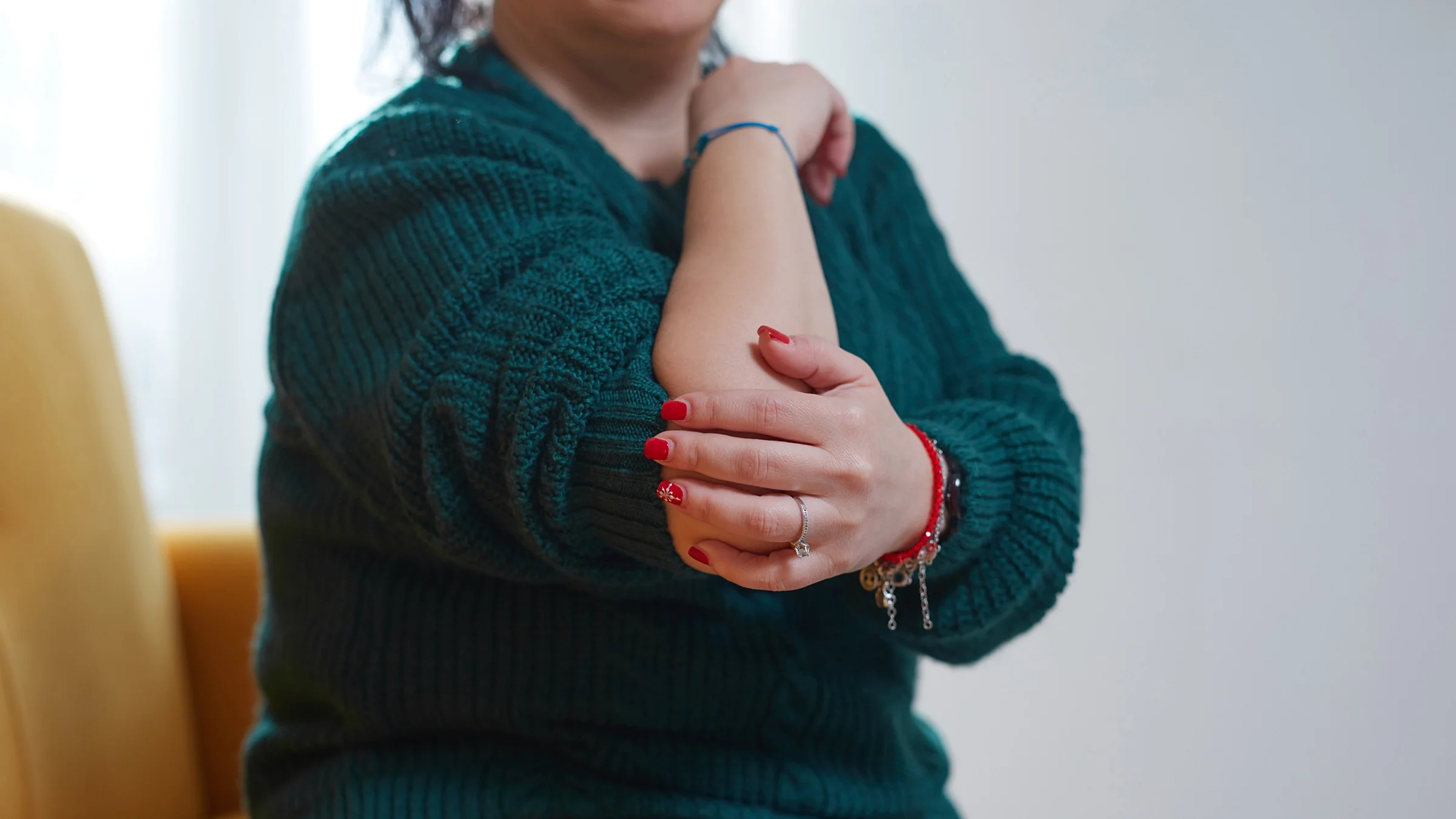 A woman experiences elbow pain at home.