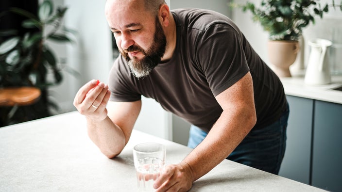 A man taking medication with a glass of water.