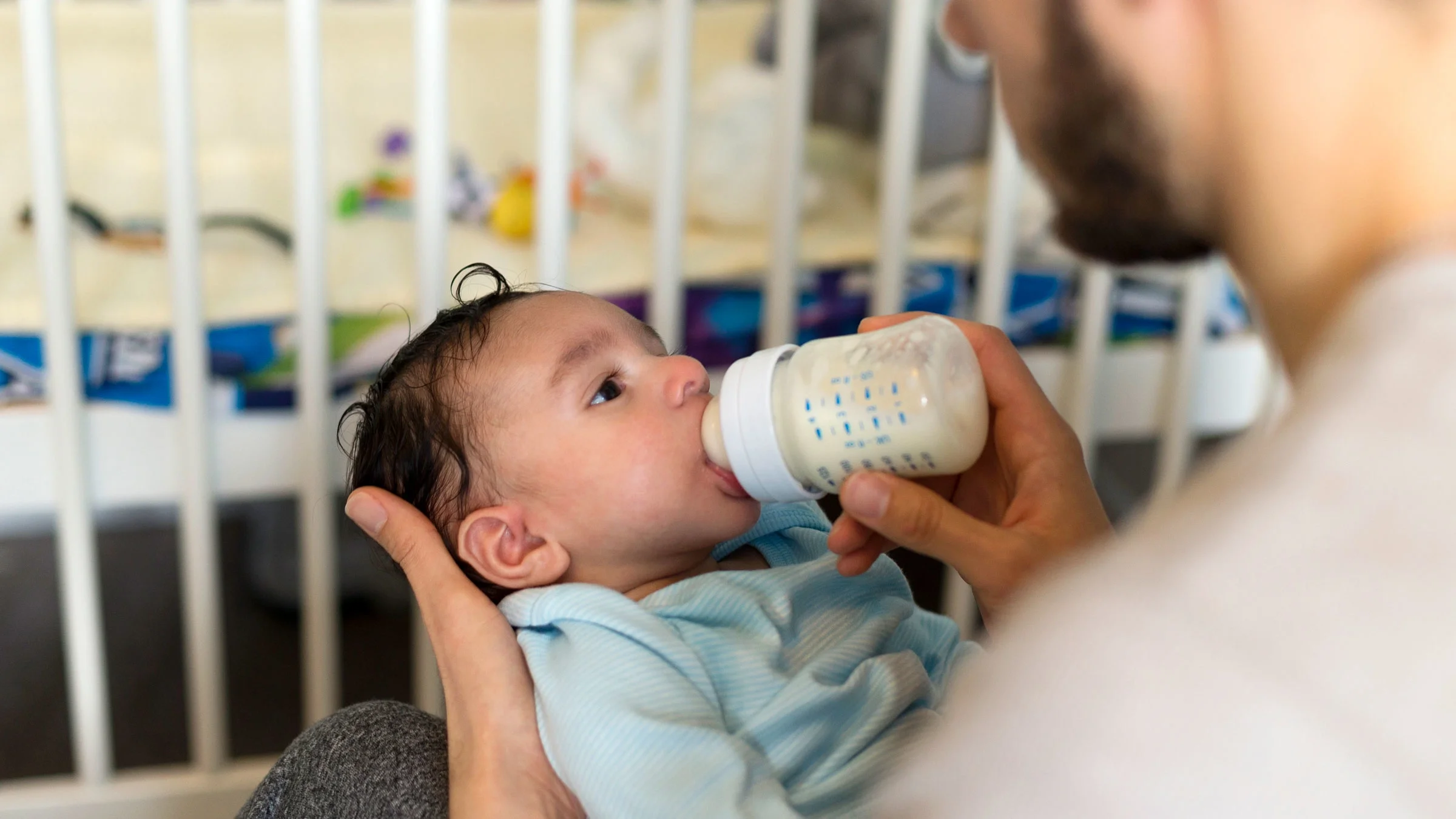 A man is feeding a baby with a bottle.