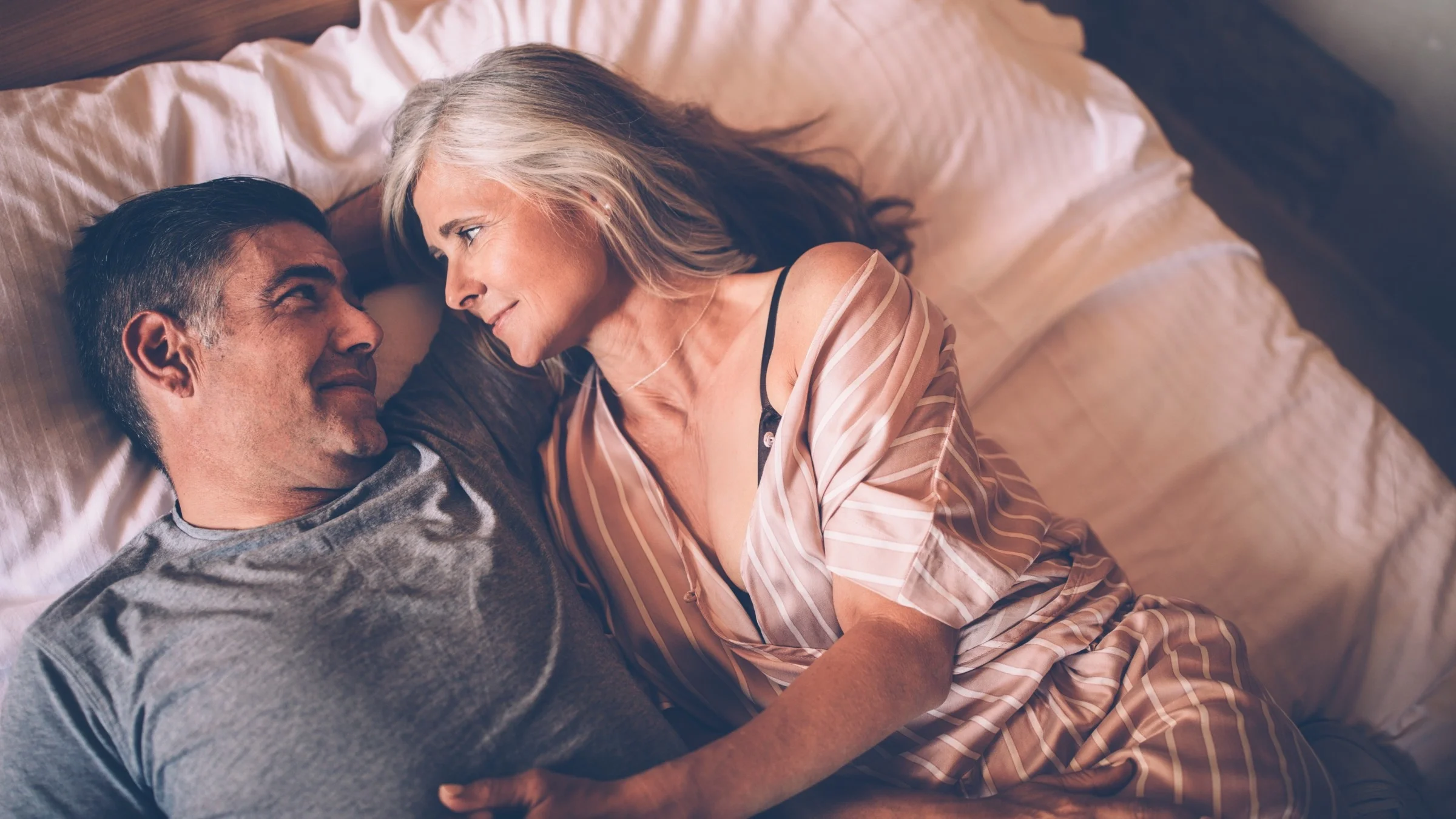 Couple talking and cuddling in bed.