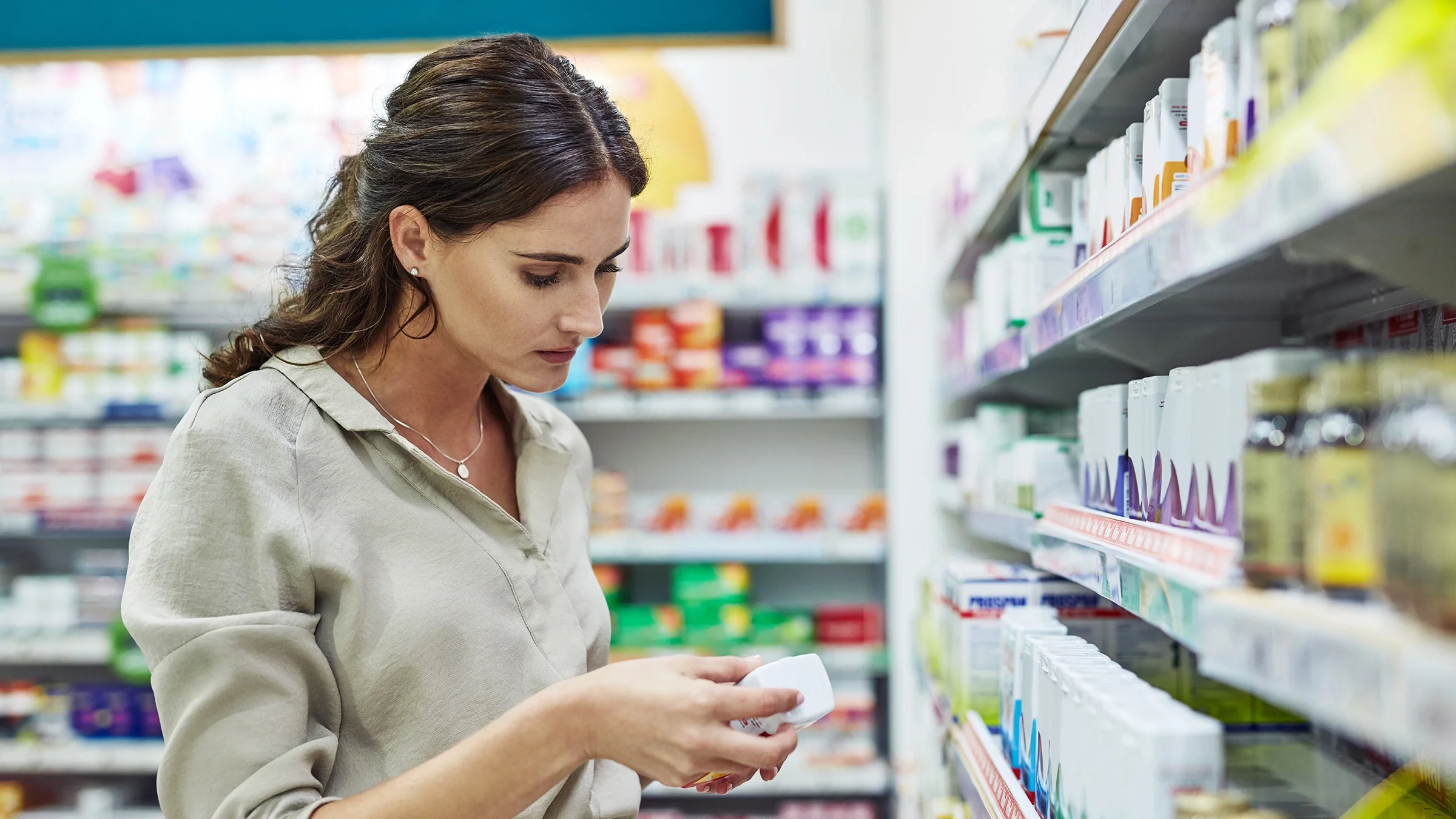 A woman looks at a bottle of medicine at a pharmacy. 