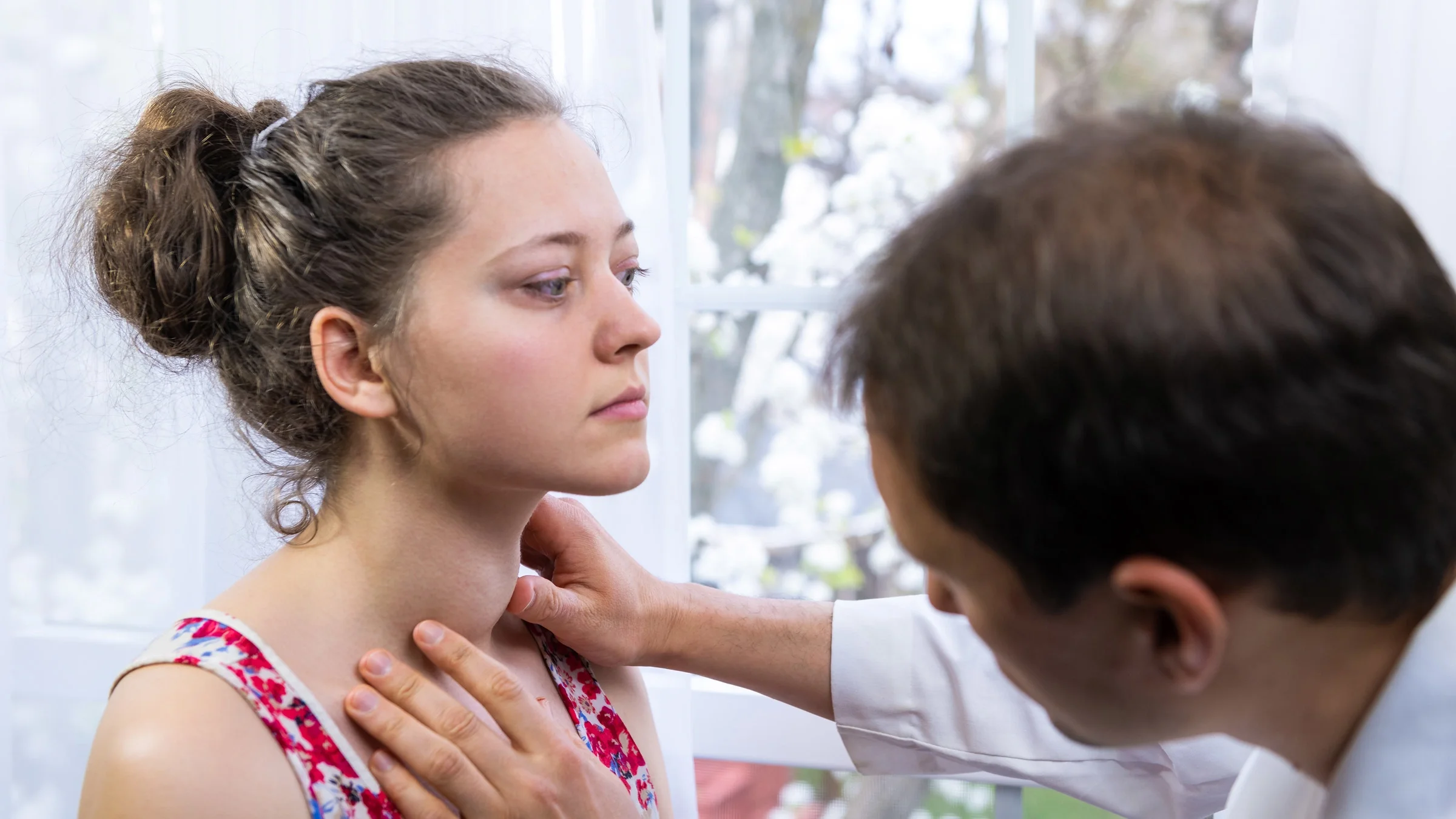A doctor inspecting the thyroid of a Graves' disease patient.
