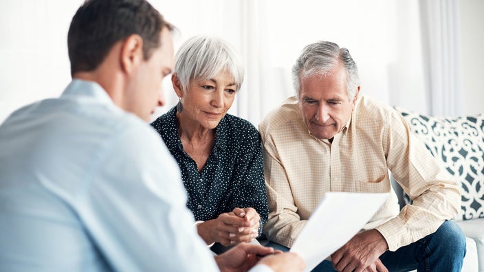 Senior couple reviewing financial paperwork with their advisor.