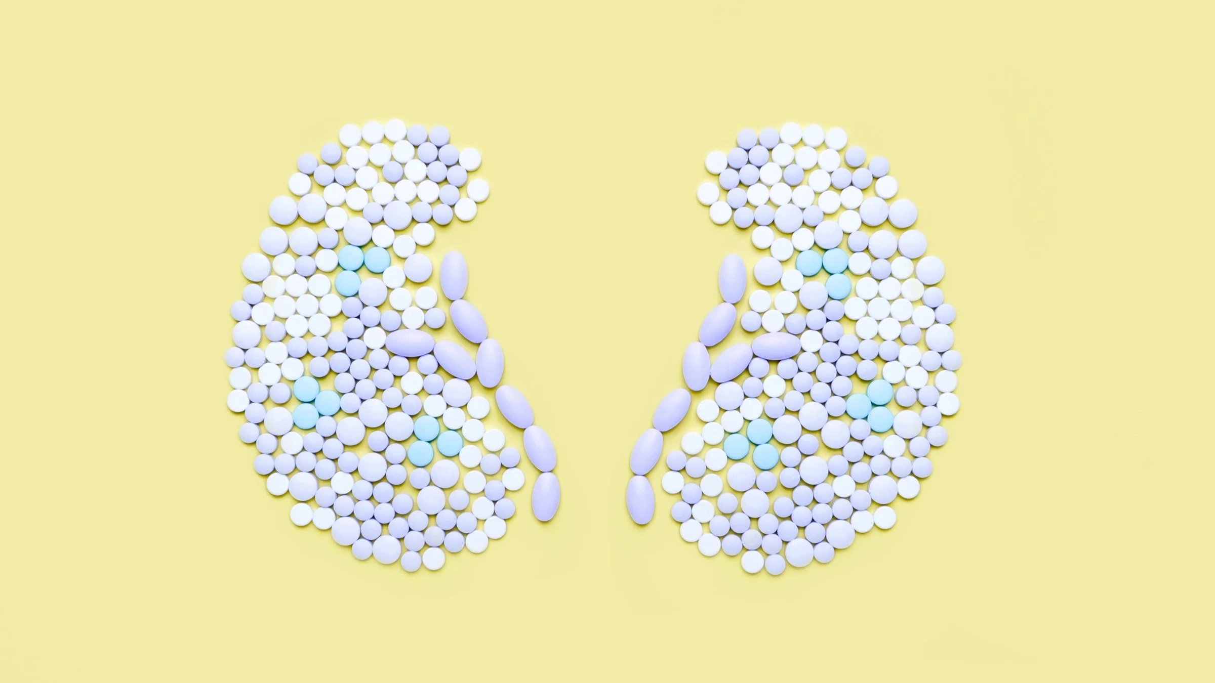 Pills form the shape of kidneys against a yellow background.