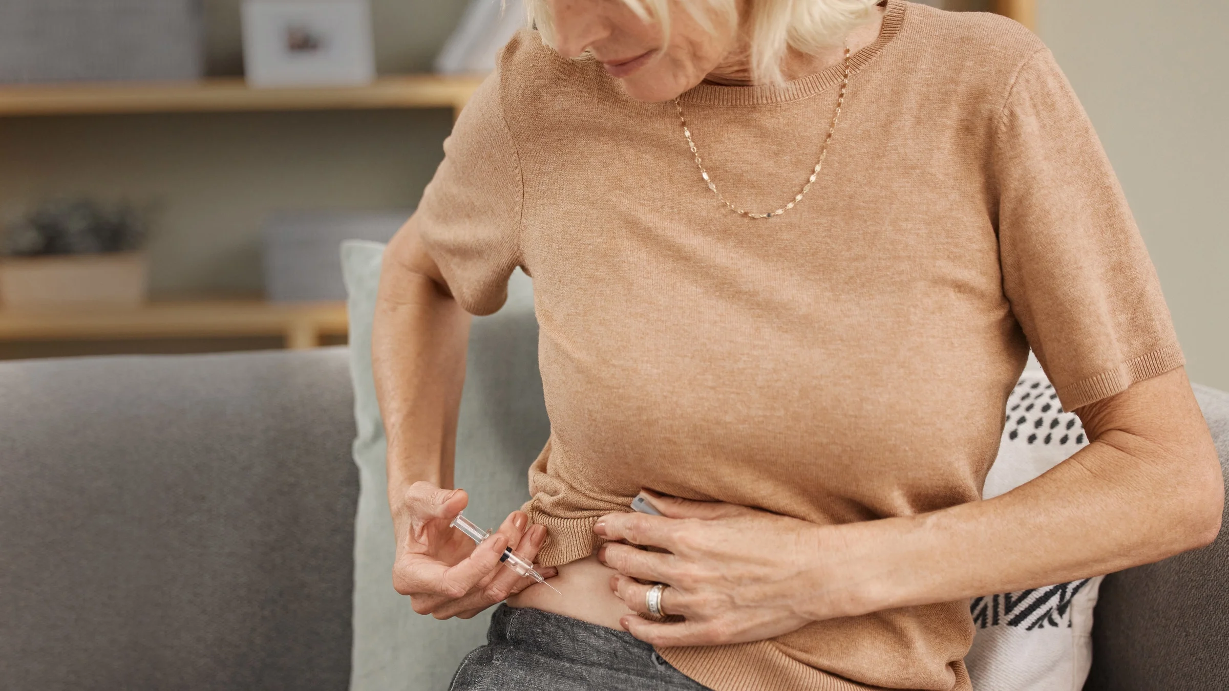 A cropped shot of someone using insulin on their couch.