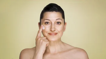 Health: Skincare: portrait woman putting on wrinkle cream 971028384