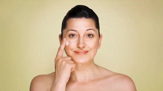 Health: Skincare: portrait woman putting on wrinkle cream 971028384