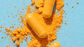 Supplements and herbs: Turmeric: yellow powder capsule pills on blue background-1308865960