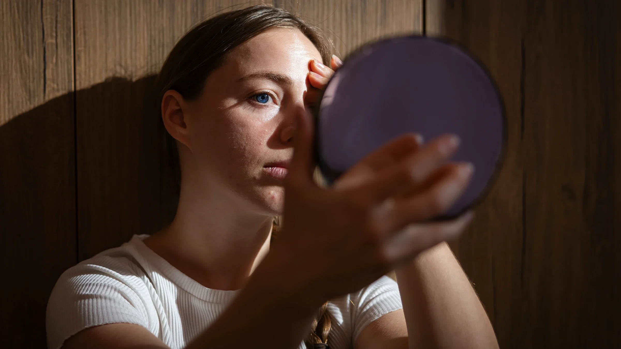 A woman is looking at her face in the mirror.