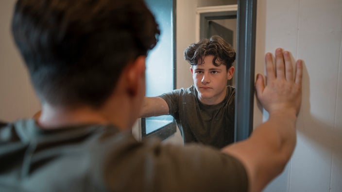 Young man looking into the mirror seriously.