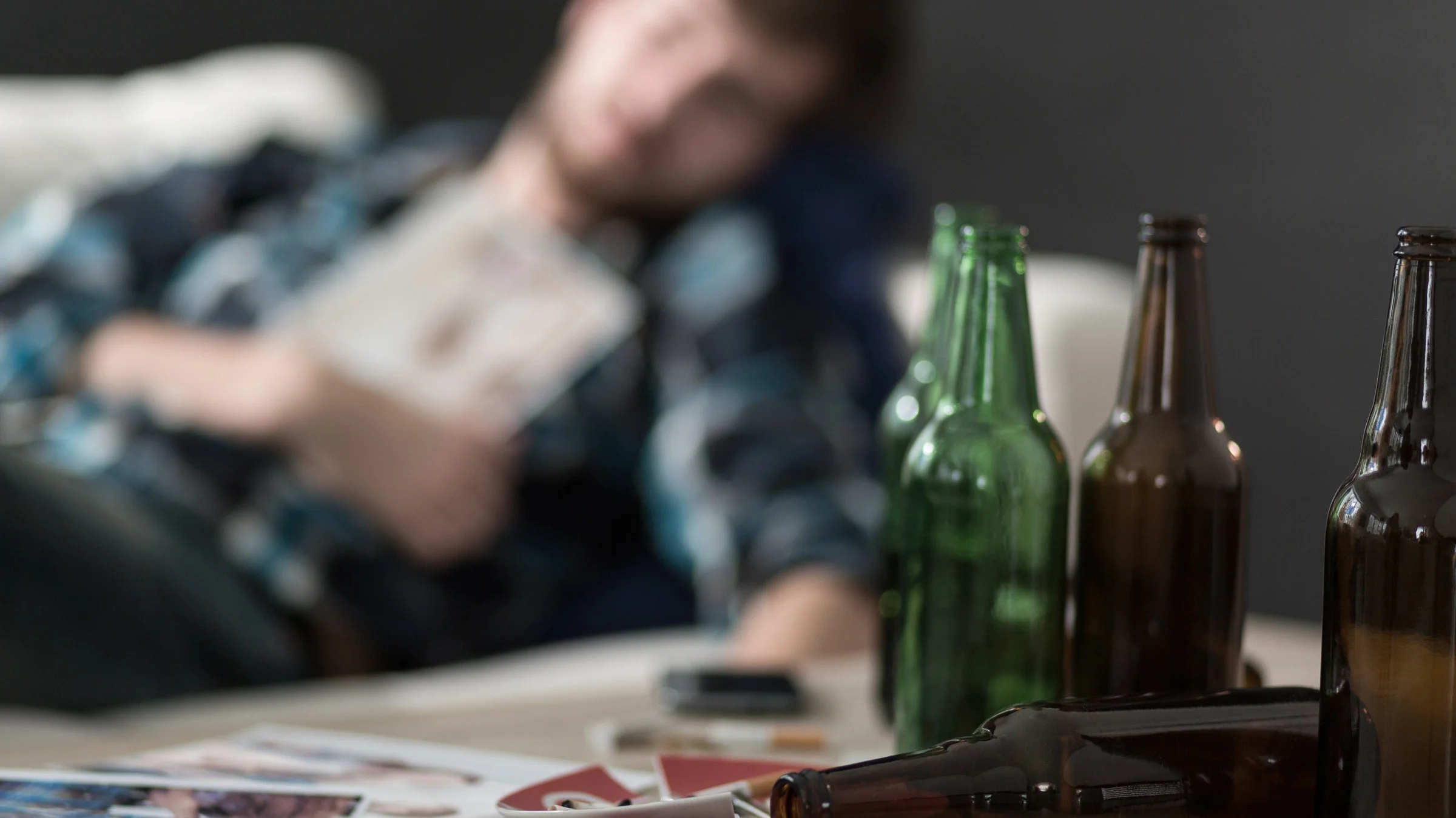 Empty beer bottles on a table. Blurry person in background.