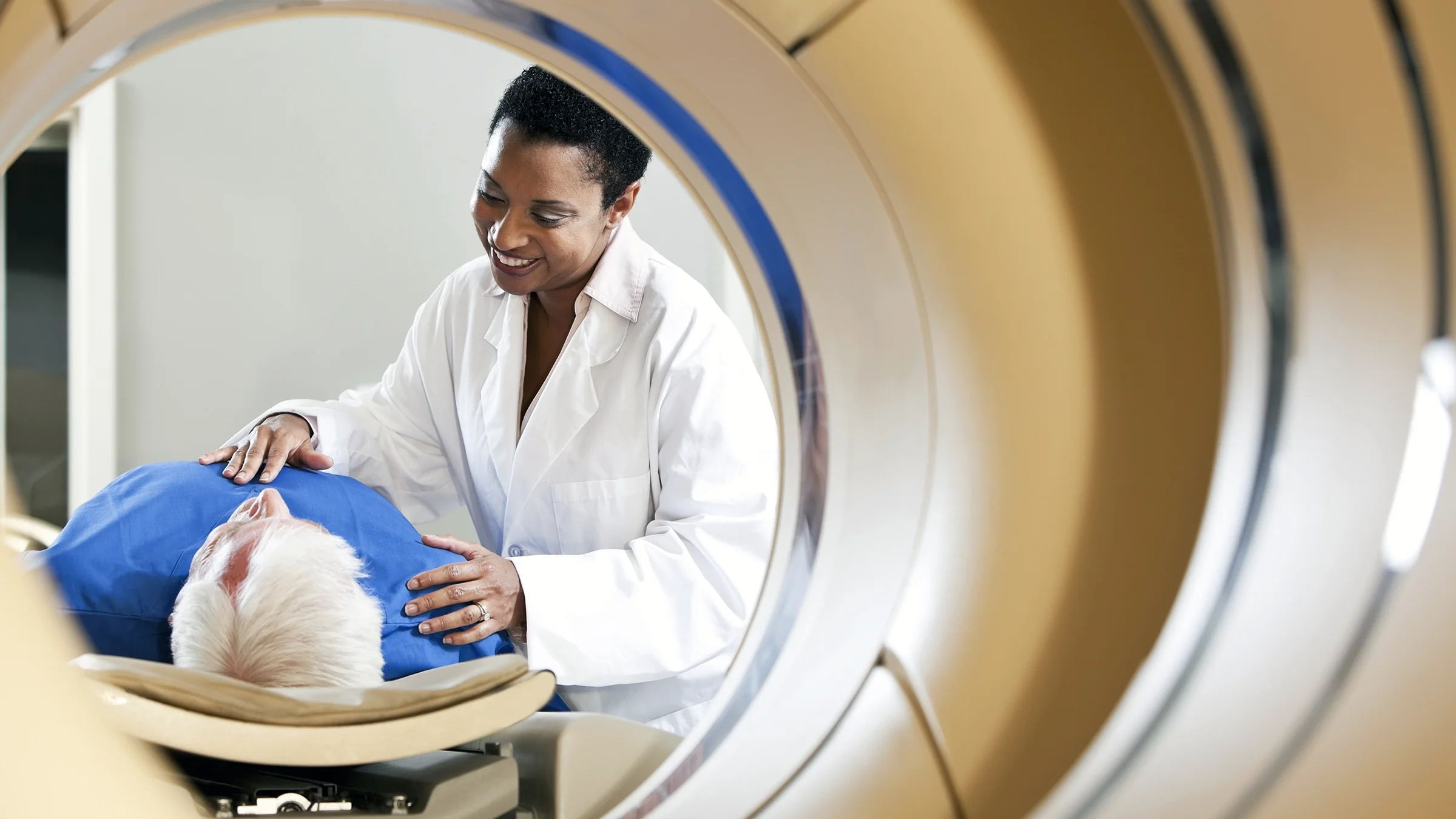 A radiologist prepares a patient for a PET-CT scanner.