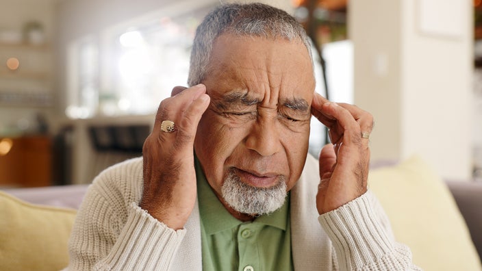 An older man rubs his temples as he experiences dizziness. 