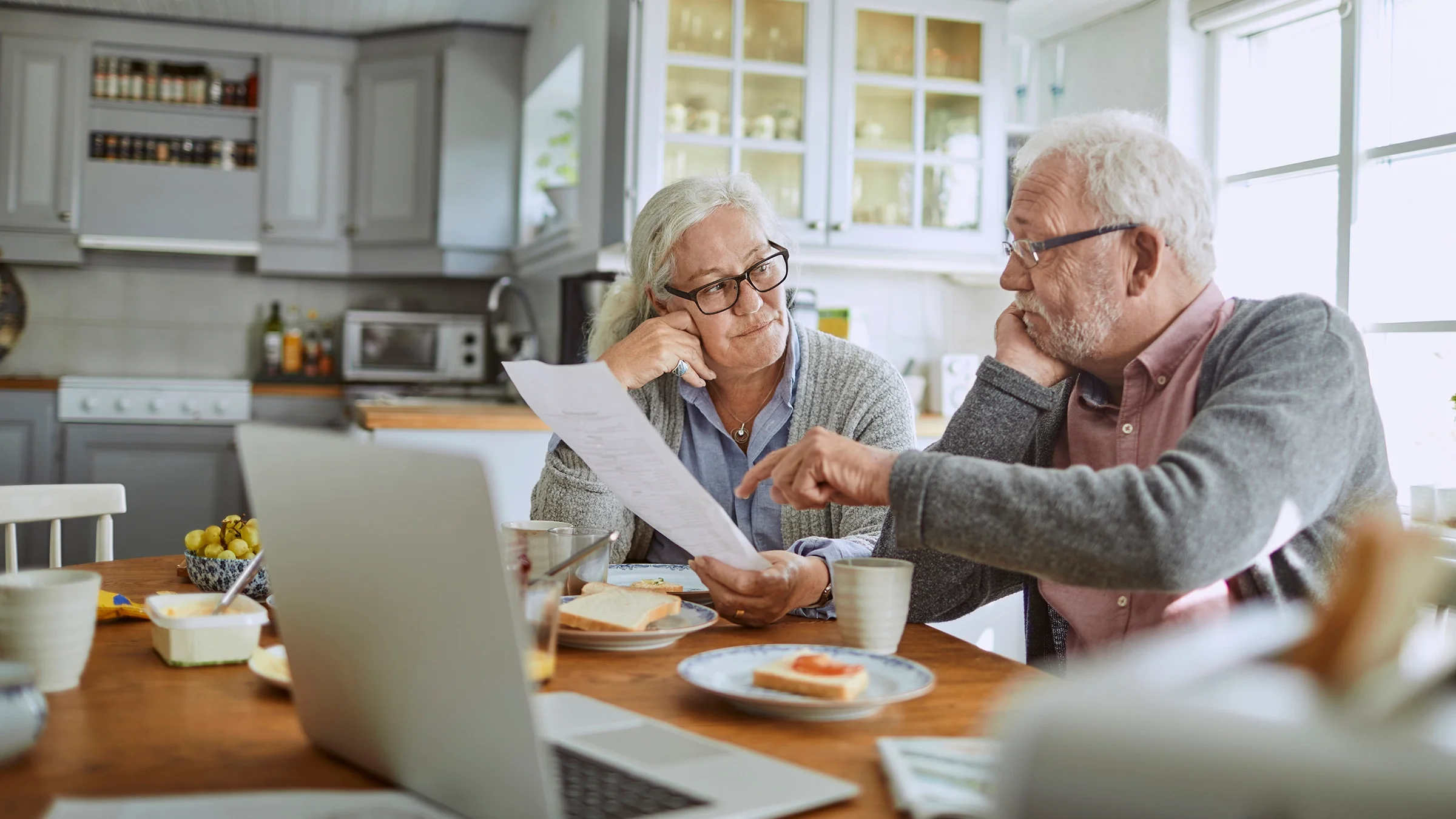 Senior couple reviewing bills at their dining table.