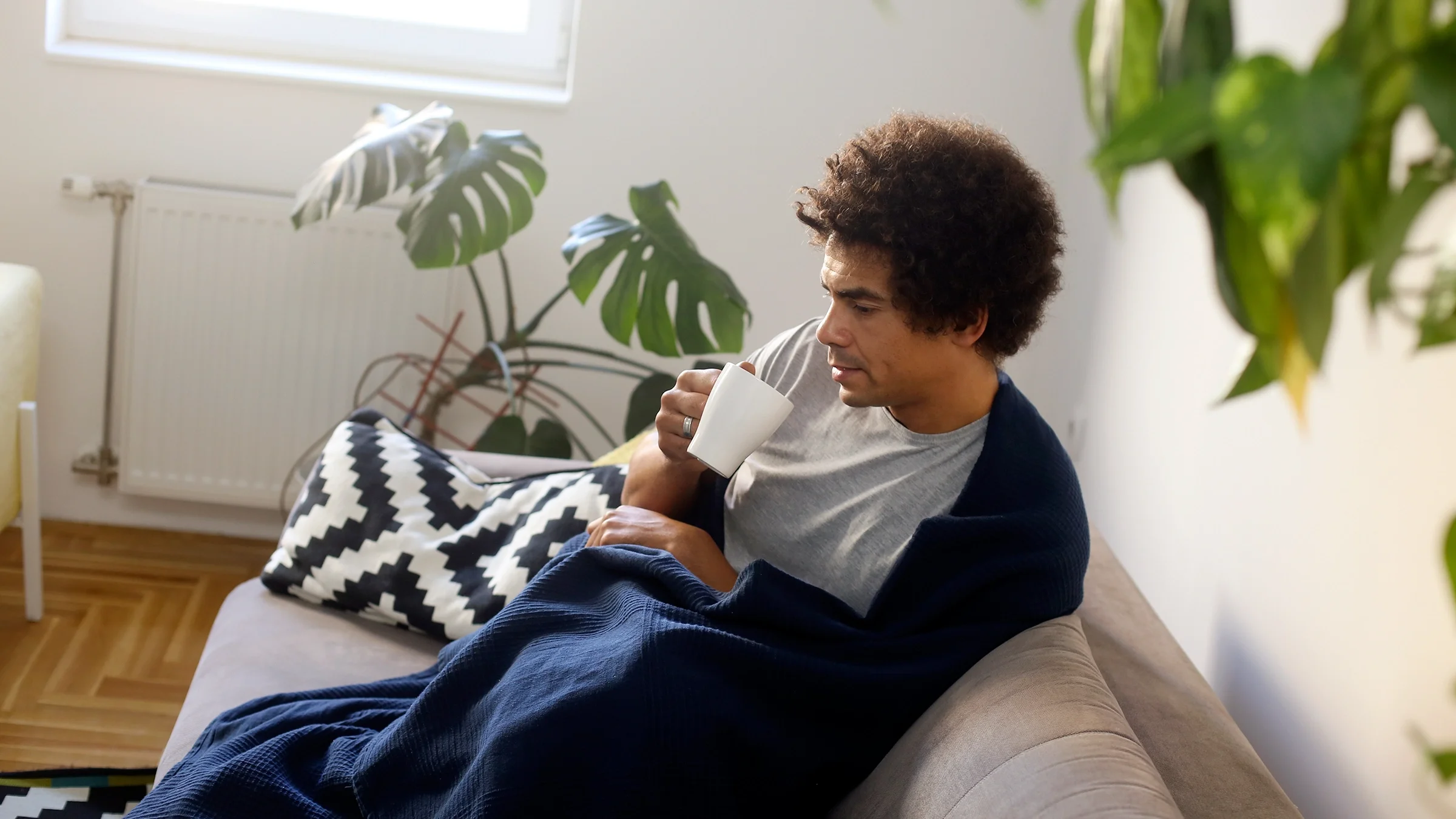 A man with a cold drinks warm tea at home, one of several doctor-recommended self-care tips.
