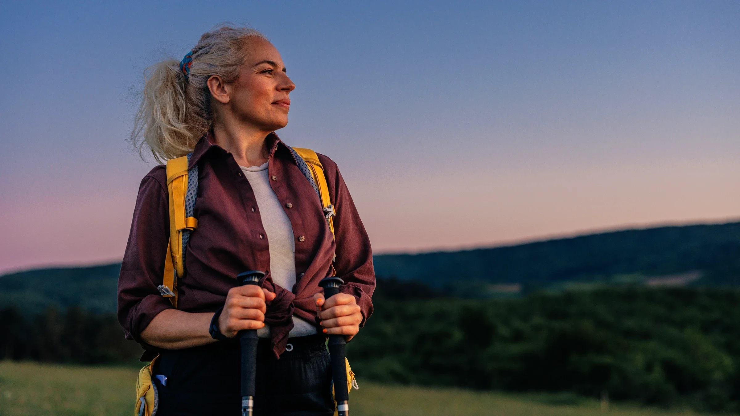 A woman is hiking with poles and smiling at the landscape.
bernardbodo/iStock via Getty Images Plus