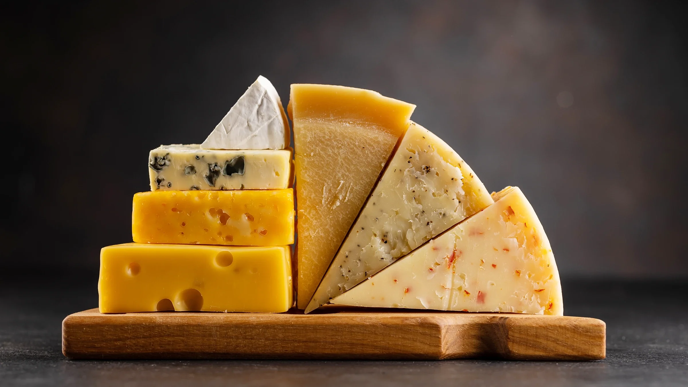 Several types of cheese are displayed on a cutting board.