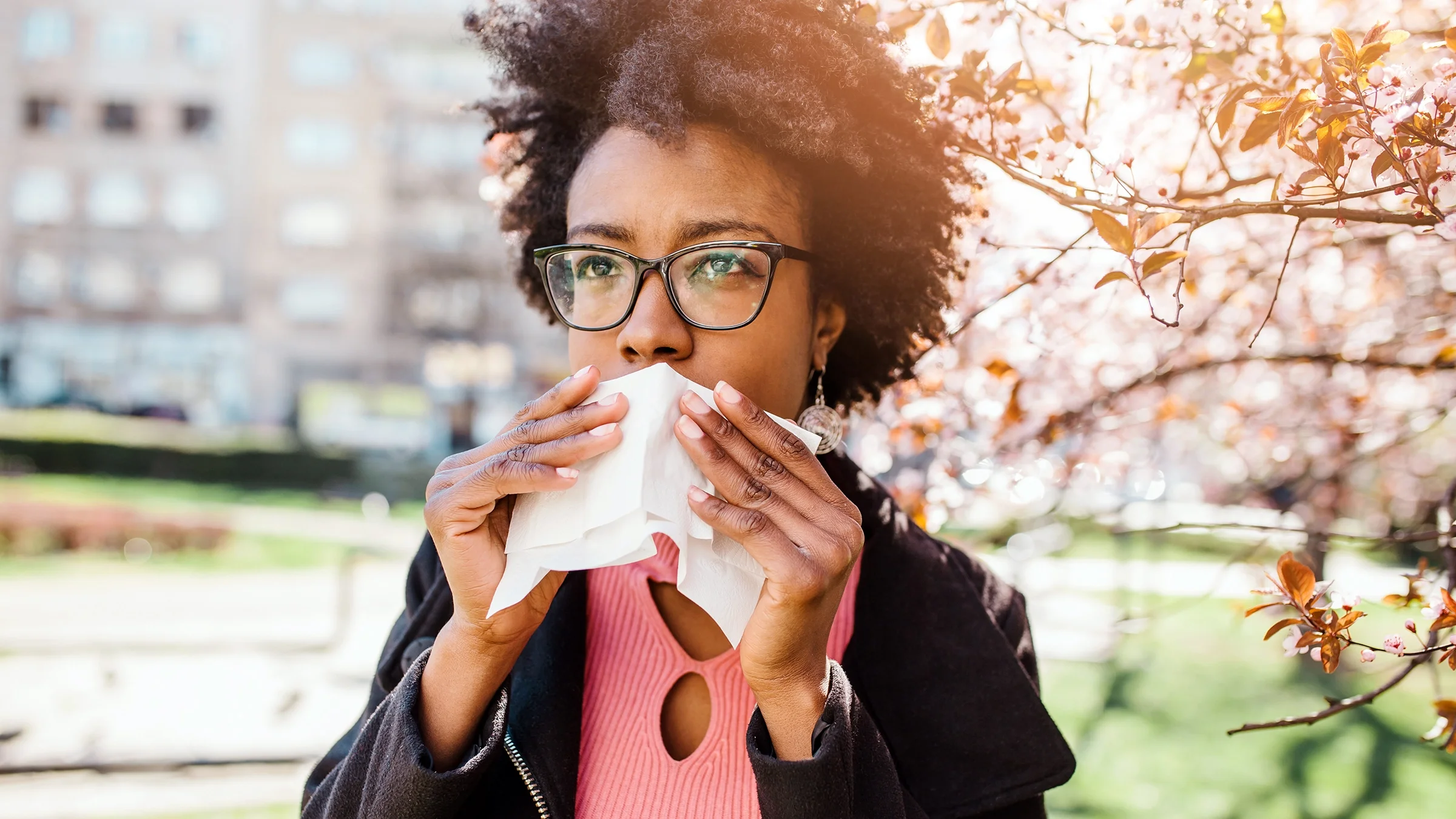 Woman blowing her nose in the park