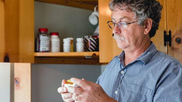 A man is taking medication in his kitchen.