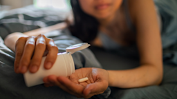 Woman taking medication laying down in bed.
vorDa/E+ via Getty Images 
