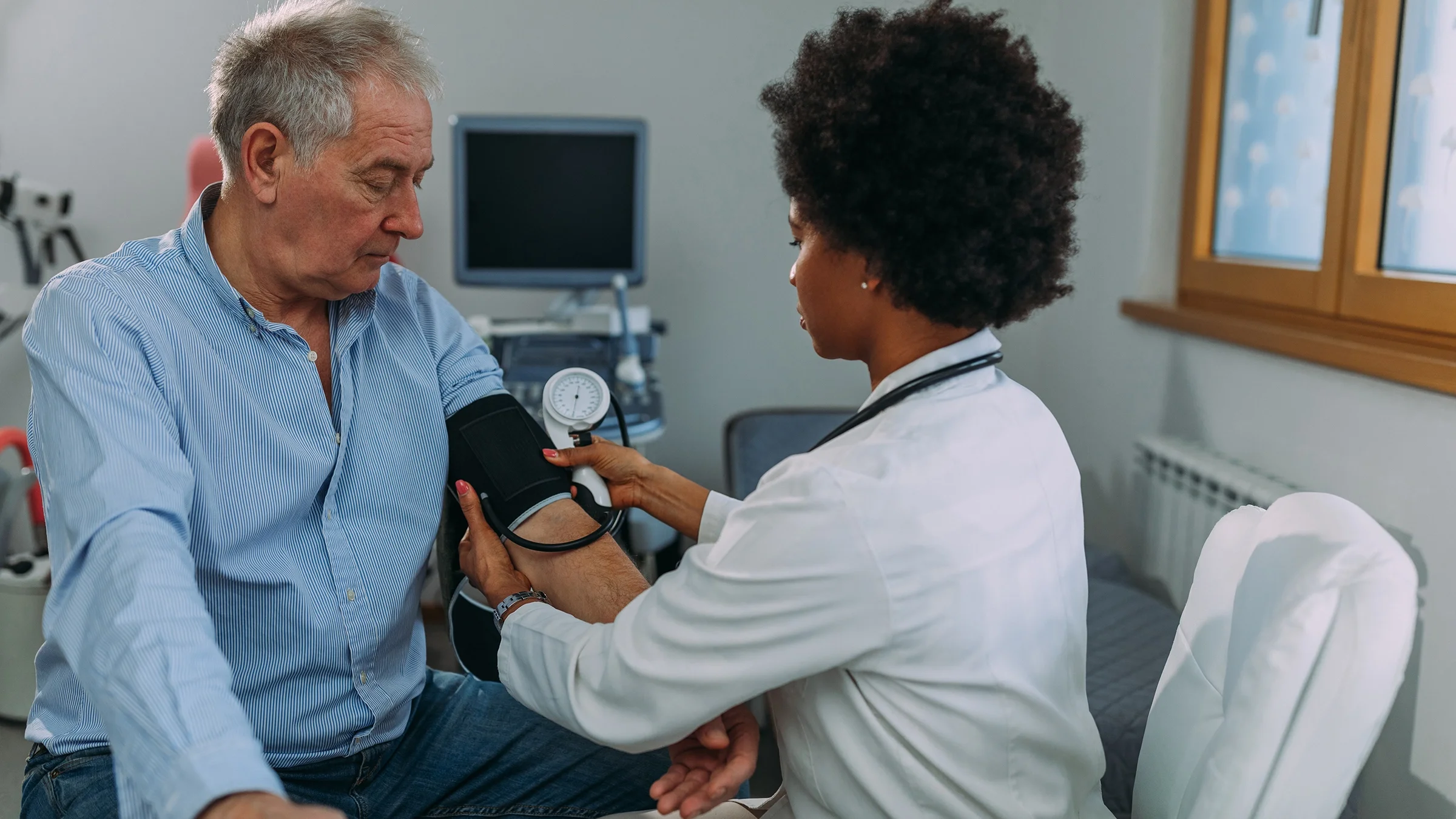 A healthcare professional measures a man’s blood pressure.