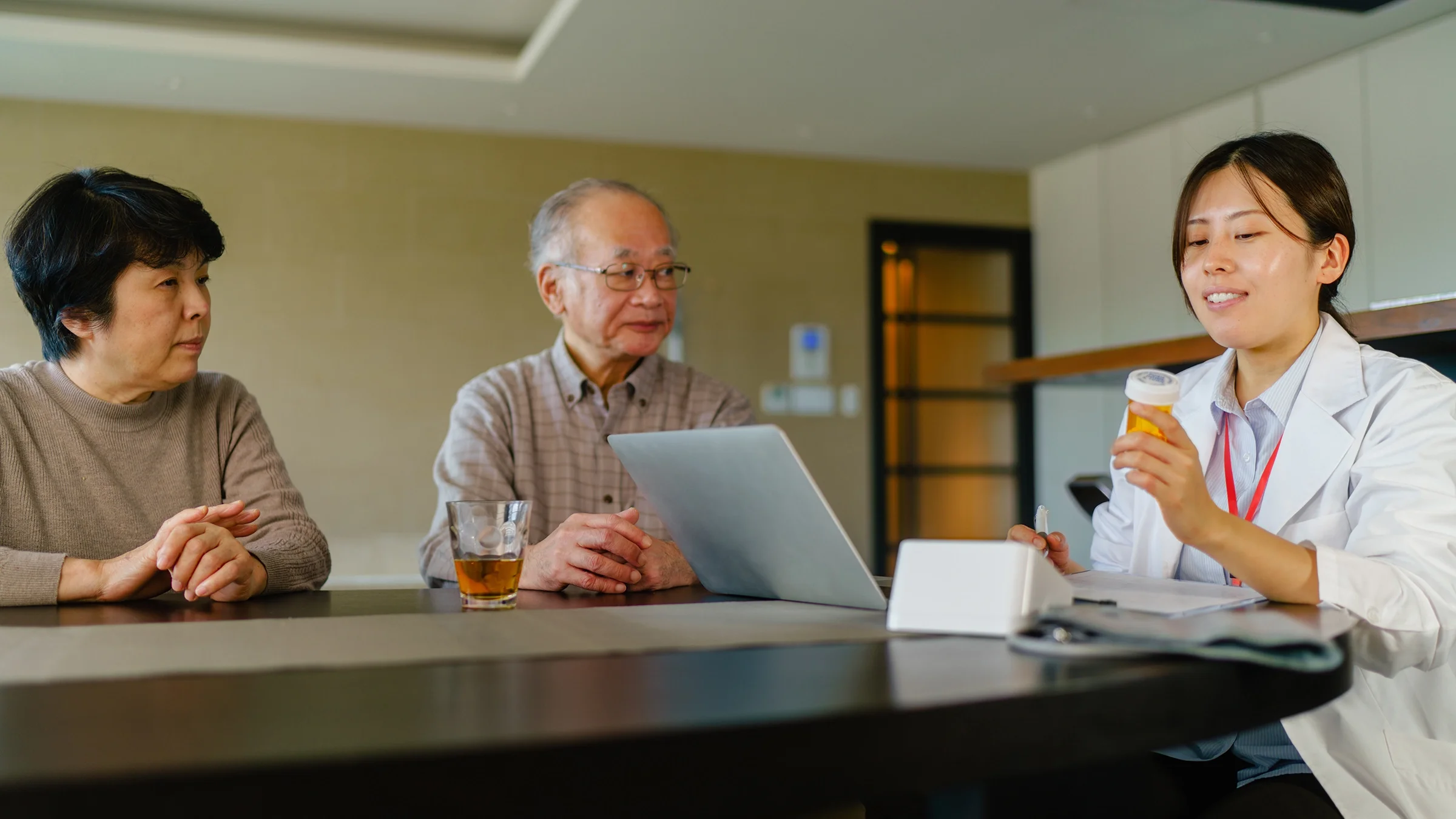 Senior couple reviewing medications with their doctor. They are all sitting around a table.