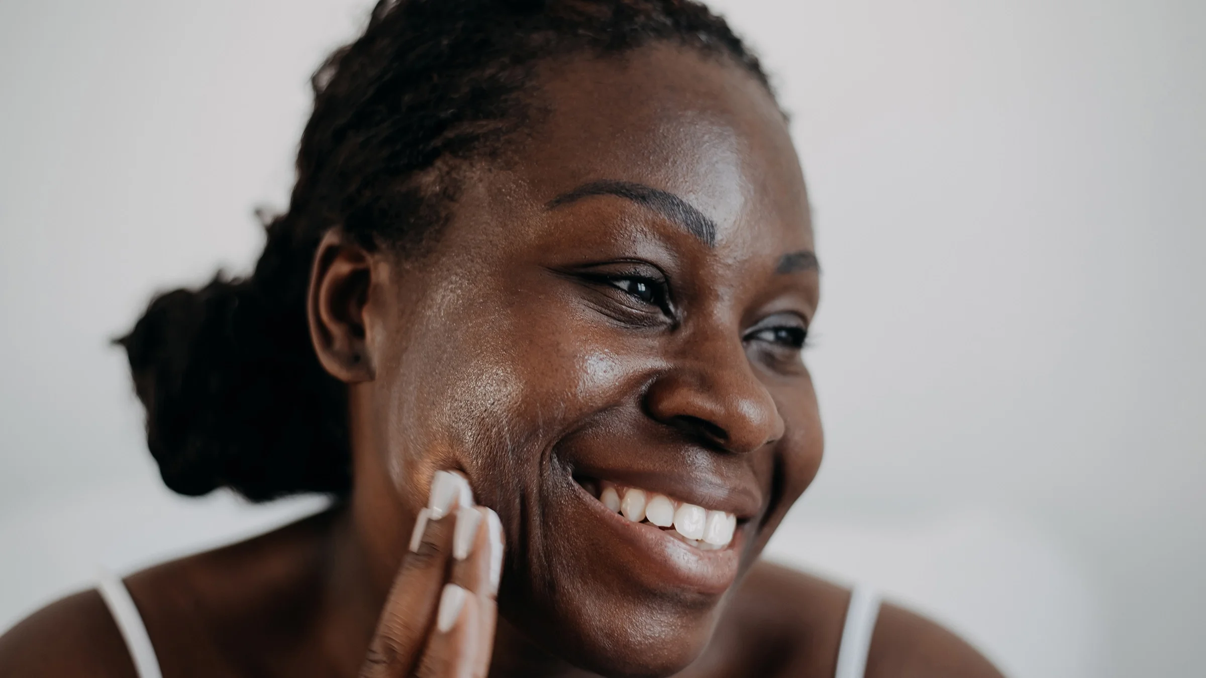 Woman putting moisturizer on her face.