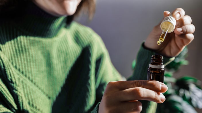 Close-up shot of a woman holding a dropper of oil.