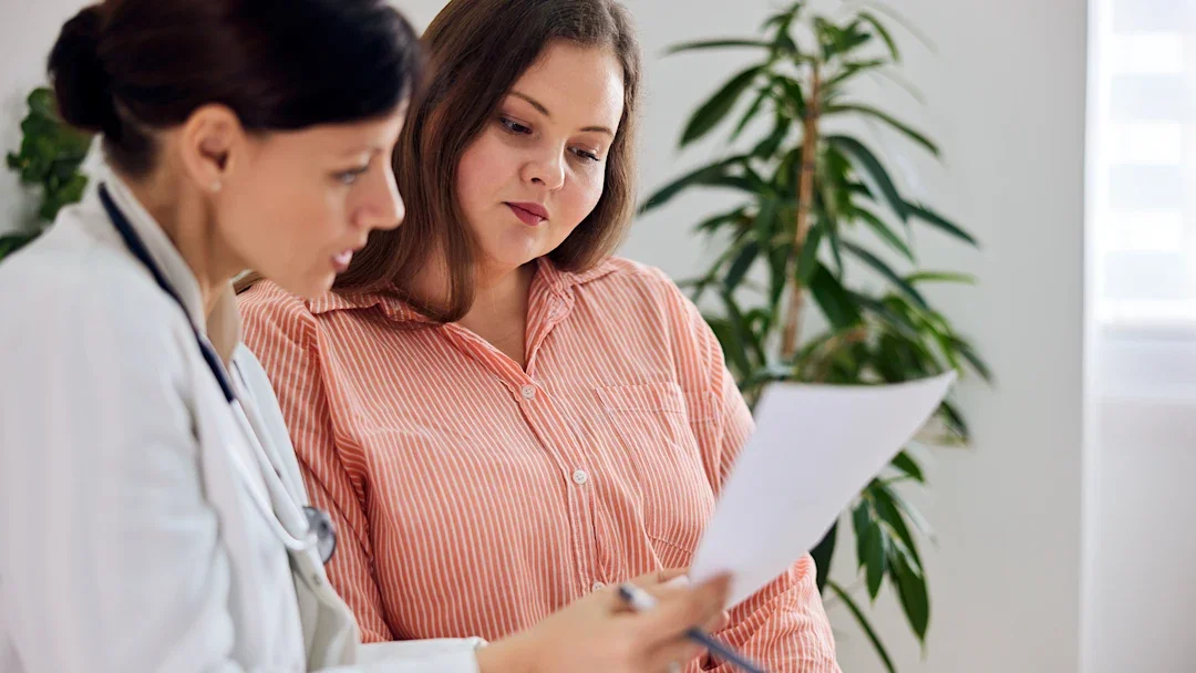 A woman is reviewing paperwork at an appointment with her healthcare provider.
nortonrsx/iStock via Getty Images Plus
