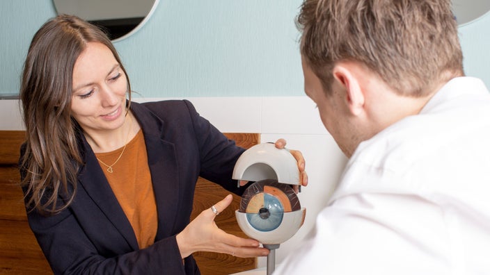 A doctor explaining eye structure using a model.