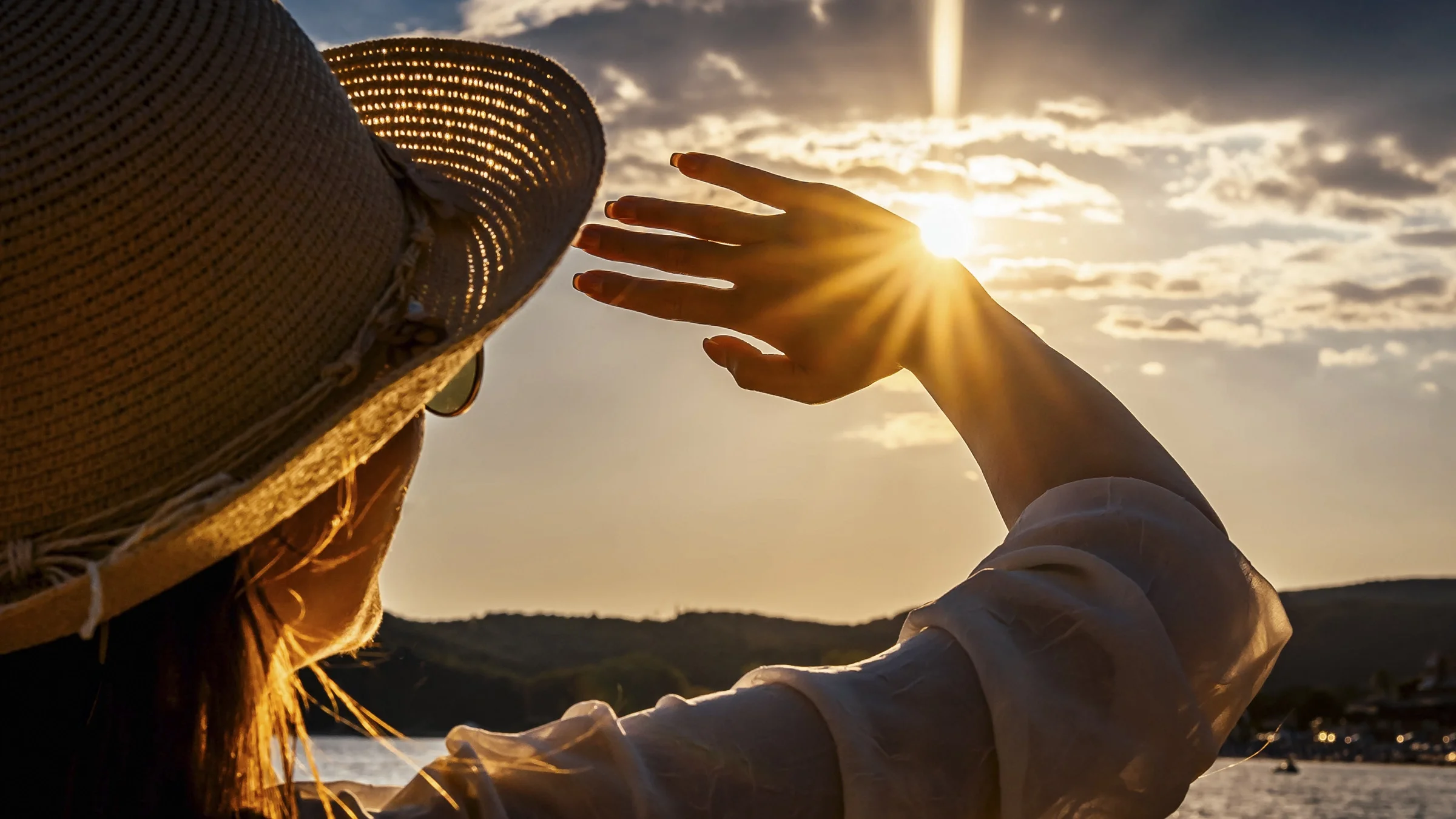 A woman is outside and trying to block the sun with her hand.