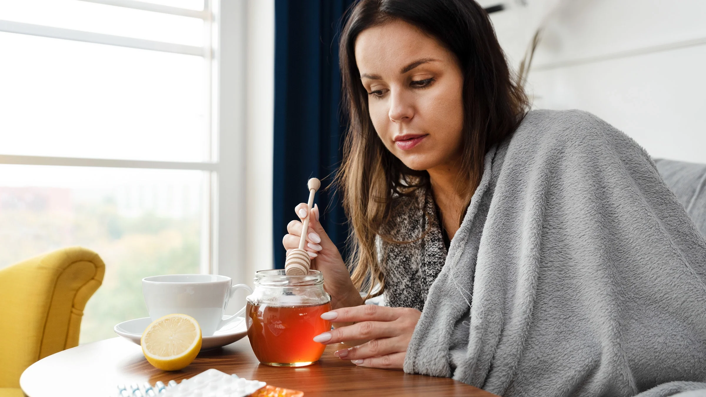 A sick person adding honey to their tea.