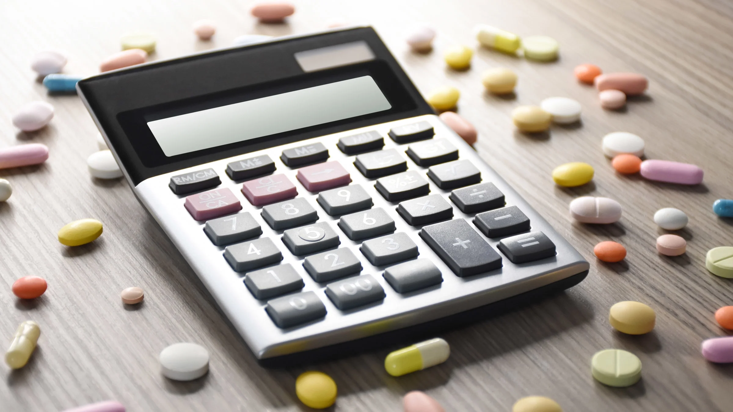 A calculator surrounded by colorful pills.