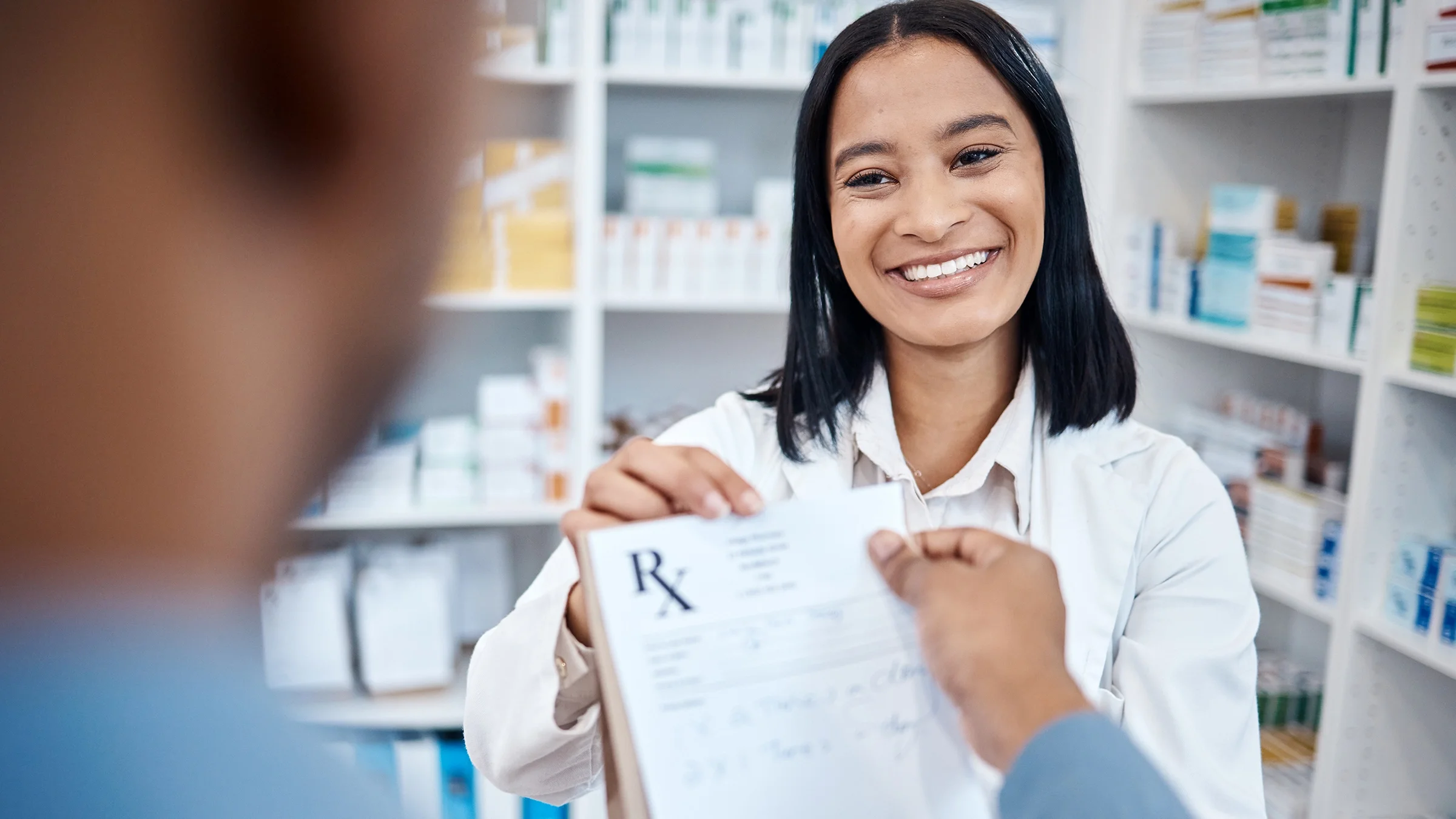 A pharmacist hands a customer their prescription.
